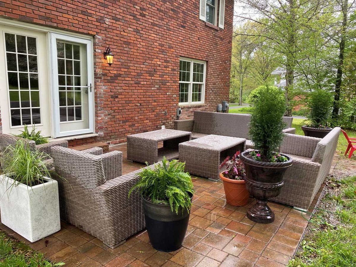Brick patio staged with container plantings and outdoor furniture